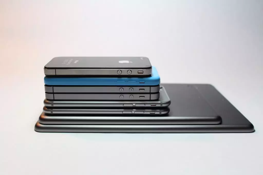 Older Apple product stack on top of each while some tries to determine the best time to buy new electronics